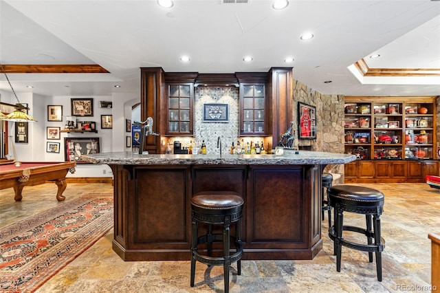 indoor wet bar with a raised ceiling, recessed lighting, pool table, decorative backsplash, and light stone finish flooring