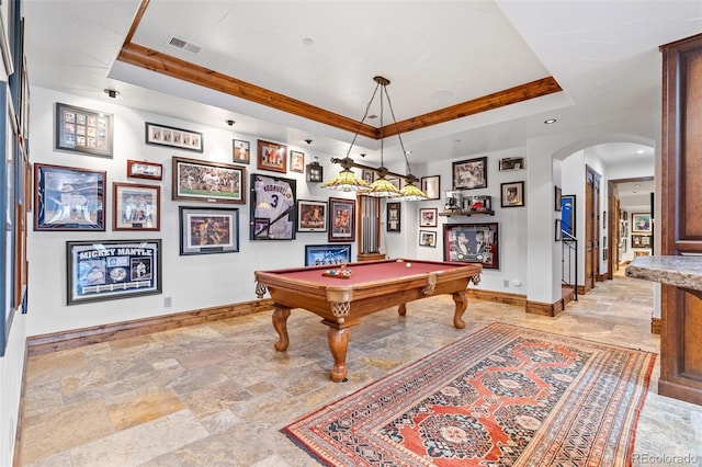 playroom with stone tile floors, baseboards, a tray ceiling, and arched walkways