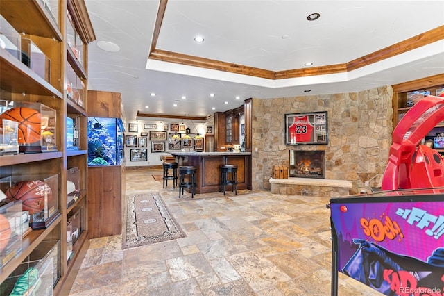 recreation room featuring a raised ceiling, stone tile floors, a community bar, recessed lighting, and a fireplace