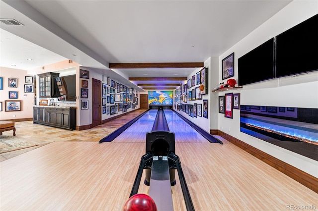 playroom with bowling, baseboards, a sink, beamed ceiling, and light wood-style floors