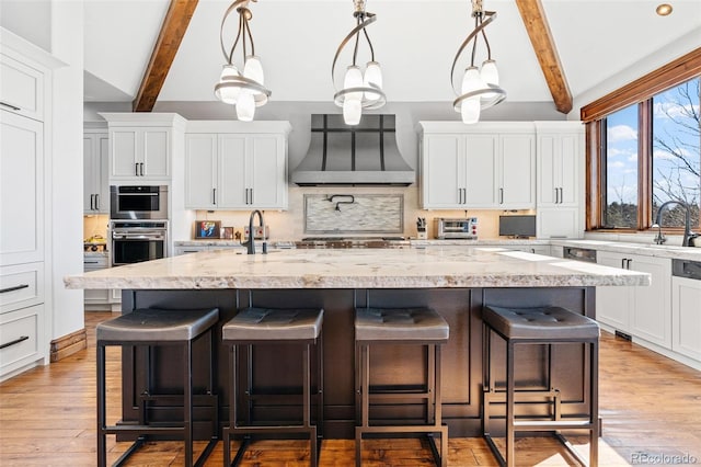 kitchen featuring wall chimney exhaust hood, backsplash, white cabinetry, and a breakfast bar area