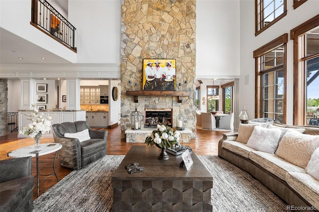 living area with a towering ceiling, a fireplace, and dark wood-style floors