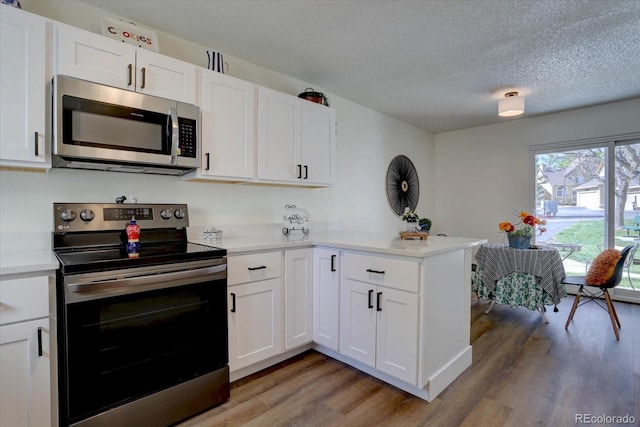 10359 W Fair Ave Unit F, Littleton, CO 80127 - kitchen featuring stainless steel appliances, light wood-type flooring, a peninsula, light countertops, and white cabinets