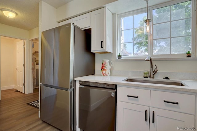 10359 W Fair Ave Unit F, Littleton, CO 80127 - kitchen featuring appliances with stainless steel finishes, a sink, white cabinetry, light countertops, and wood finished floors