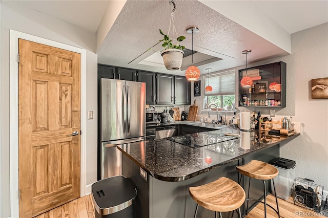 6213 Willow Ln, Boulder, CO 80301 - kitchen featuring stainless steel appliances, a peninsula, dark stone counters, light wood-style floors, and a raised ceiling