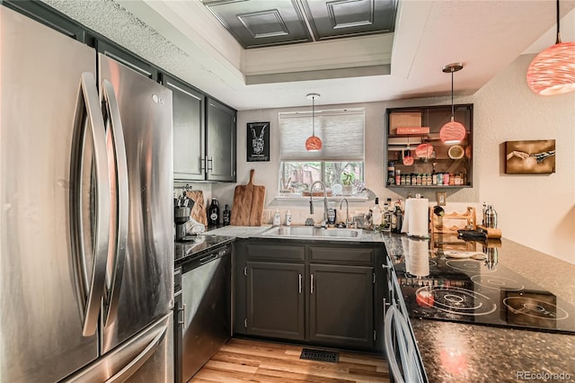 6213 Willow Ln, Boulder, CO 80301 - kitchen with stainless steel appliances, a tray ceiling, light wood finished floors, decorative light fixtures, and dark stone counters