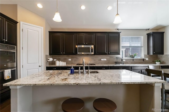 2724 Rising Moon Way, Castle Rock, CO 80109 - kitchen featuring appliances with stainless steel finishes, a sink, decorative backsplash, a kitchen breakfast bar, and pendant lighting