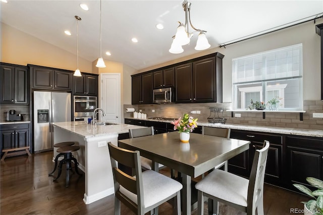 2724 Rising Moon Way, Castle Rock, CO 80109 - kitchen with appliances with stainless steel finishes, a sink, decorative backsplash, decorative light fixtures, and a center island with sink