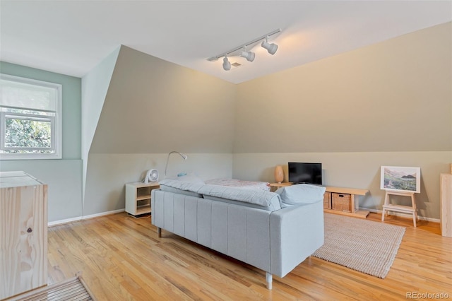 living room with light hardwood / wood-style floors, vaulted ceiling, and track lighting