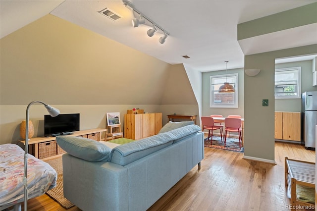 living room with vaulted ceiling, light hardwood / wood-style floors, and track lighting