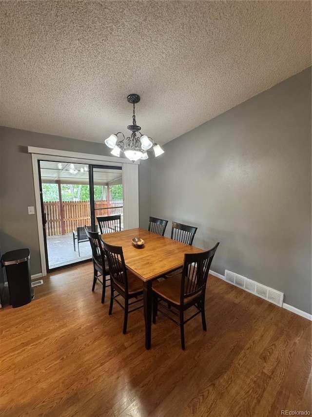 7020 W Portland Ave, Littleton, CO 80128 - dining area featuring a chandelier, wood finished floors, and a textured ceiling