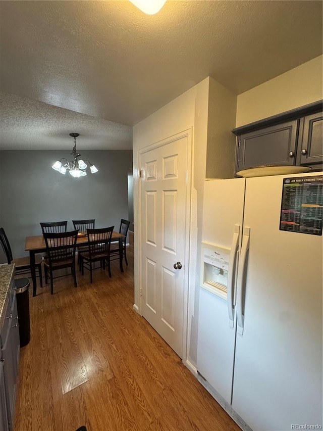 7020 W Portland Ave, Littleton, CO 80128 - kitchen with white refrigerator with ice dispenser, a chandelier, wood finished floors, and a textured ceiling