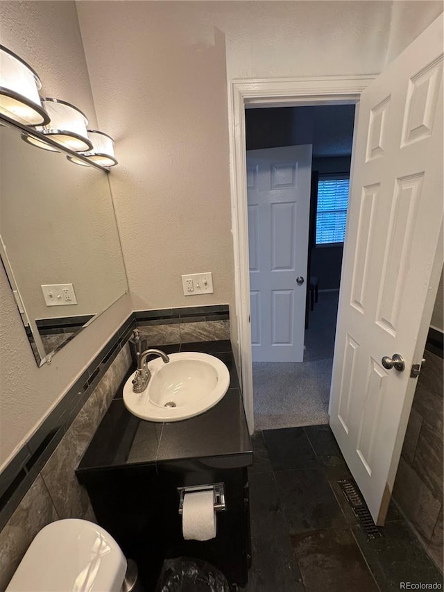 7020 W Portland Ave, Littleton, CO 80128 - bathroom with vanity, tile walls, wainscoting, and tile patterned floors