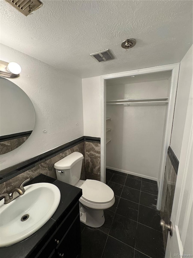7020 W Portland Ave, Littleton, CO 80128 - bathroom featuring tile walls, vanity, a wainscoted wall, a textured ceiling, and tile patterned floors