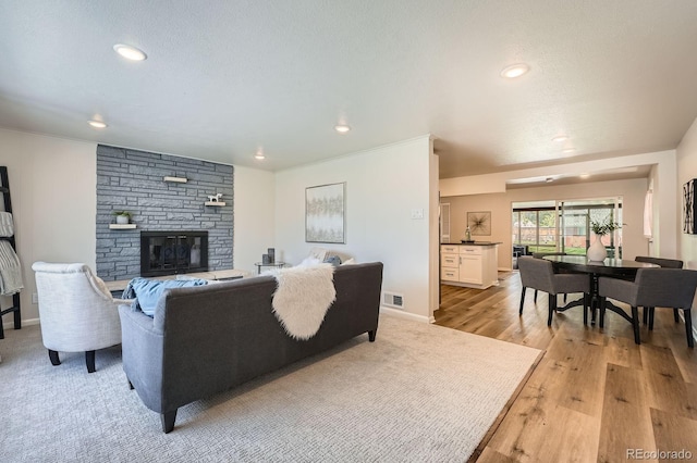 14505 W 52nd Ave, Arvada, CO 80002 - living room featuring a fireplace, recessed lighting, light wood-style flooring, baseboards, and a textured ceiling