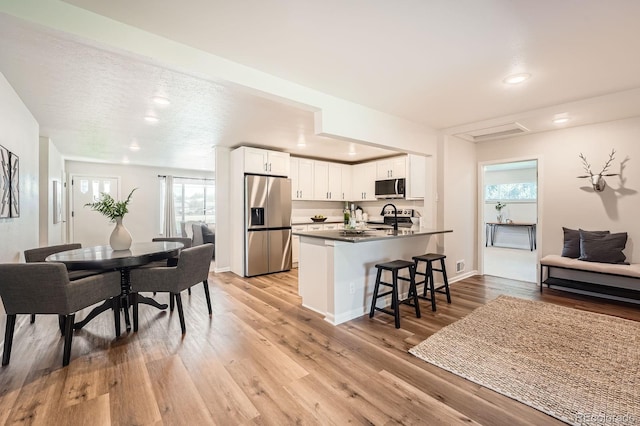 14505 W 52nd Ave, Arvada, CO 80002 - kitchen with appliances with stainless steel finishes, a kitchen breakfast bar, white cabinets, plenty of natural light, and recessed lighting