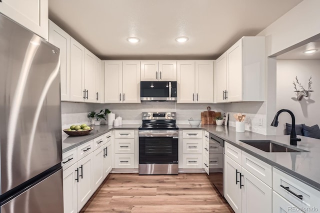 14505 W 52nd Ave, Arvada, CO 80002 - kitchen with stainless steel appliances, a sink, light wood-style flooring, white cabinetry, and recessed lighting