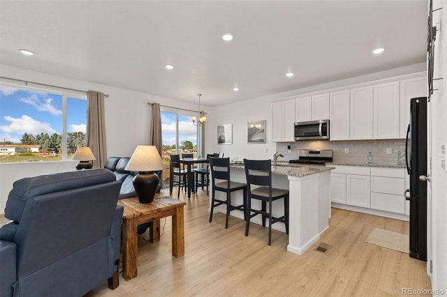 kitchen with pendant lighting, a center island with sink, appliances with stainless steel finishes, and a wealth of natural light