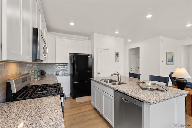 kitchen featuring white cabinets, an island with sink, sink, stainless steel appliances, and light hardwood / wood-style floors