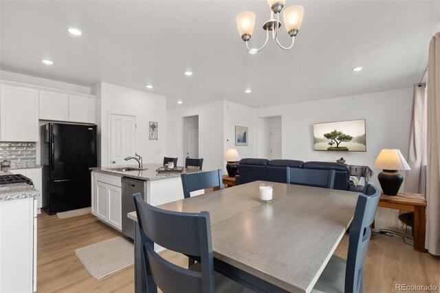 dining room featuring sink, a chandelier, and light hardwood / wood-style flooring