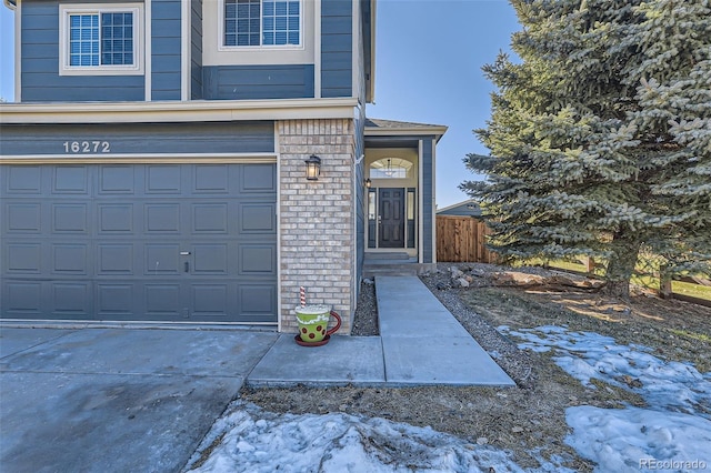 snow covered property entrance featuring a garage