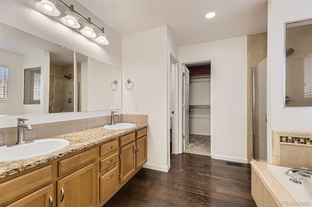 bathroom featuring hardwood / wood-style flooring, vanity, and separate shower and tub