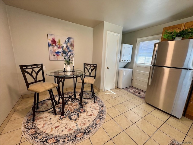 dining space with light tile patterned floors and stacked washer / drying machine