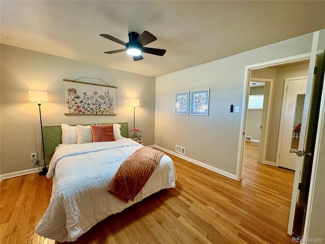 bedroom with ceiling fan, wood finished floors, visible vents, and baseboards