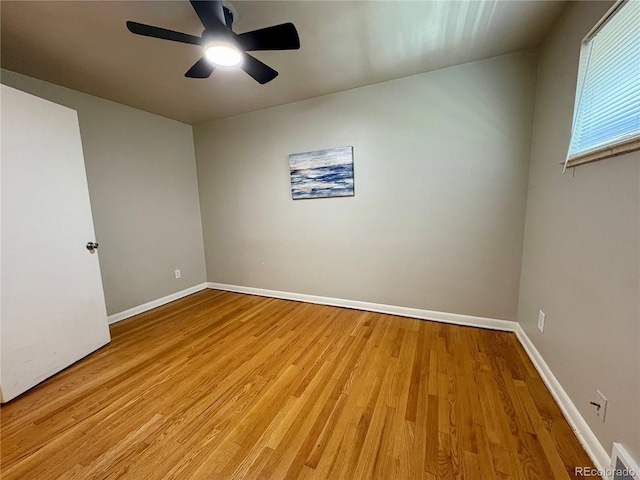 empty room with ceiling fan, light wood finished floors, and baseboards