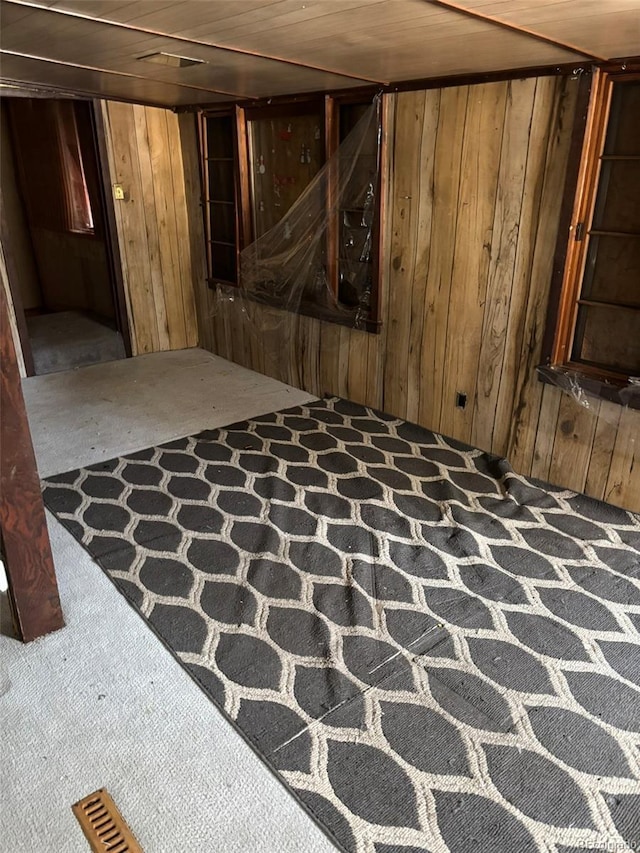 basement with carpet, wood ceiling, and wood walls