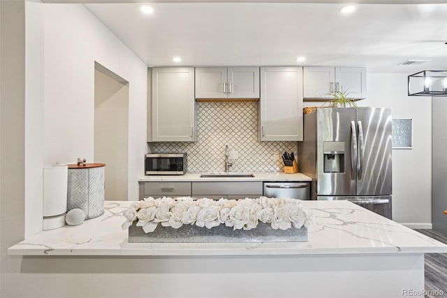 7995 E Mississippi Ave Unit F23, Denver, CO 80247 - kitchen with appliances with stainless steel finishes, a sink, gray cabinetry, decorative backsplash, and light stone countertops