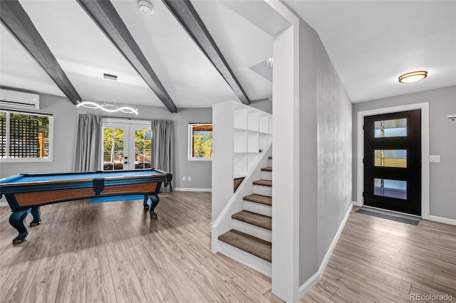 game room featuring wood finished floors, french doors, baseboards, and a wall mounted air conditioner