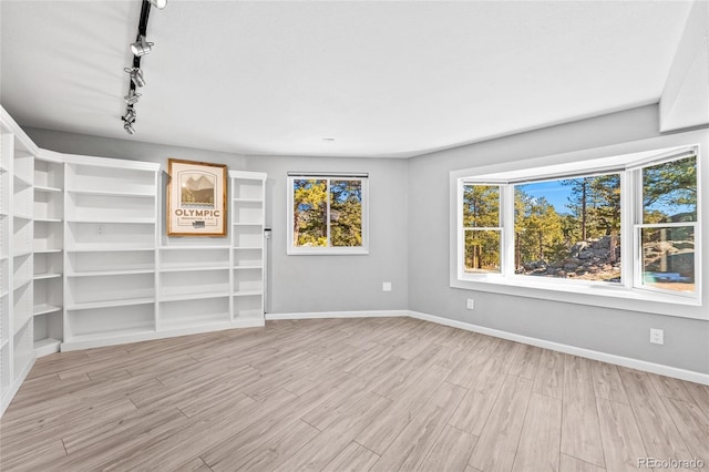 unfurnished room featuring light wood-type flooring, rail lighting, and baseboards