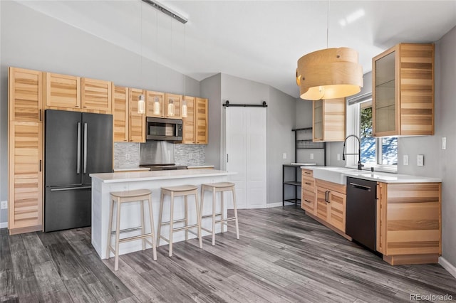 kitchen featuring refrigerator, stainless steel microwave, a barn door, a sink, and dishwasher