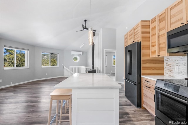 kitchen featuring a breakfast bar, backsplash, light brown cabinetry, open floor plan, and black appliances