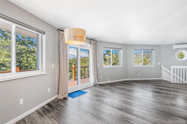 interior space with wood finished floors, baseboards, and a wall mounted AC