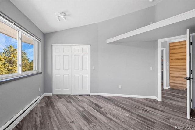 unfurnished bedroom with lofted ceiling, a baseboard radiator, baseboards, a closet, and dark wood finished floors