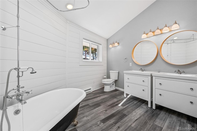 bathroom featuring two vanities, toilet, vaulted ceiling, a sink, and wood finished floors