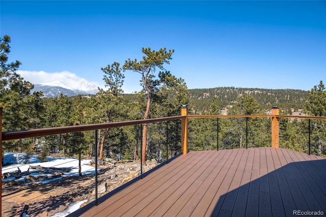 wooden deck featuring a forest view and a mountain view