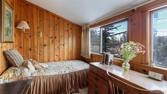 carpeted bedroom with wooden walls and lofted ceiling