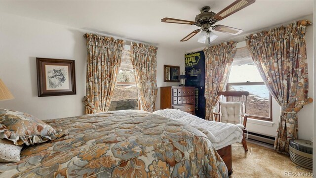 carpeted bedroom featuring baseboard heating, multiple windows, and ceiling fan