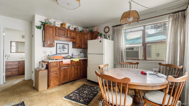 kitchen featuring light carpet, cooling unit, hanging light fixtures, and white refrigerator