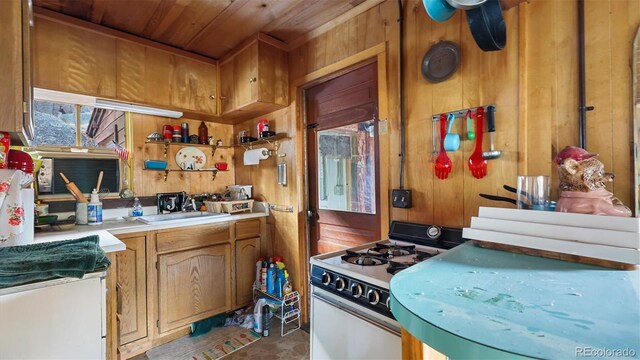 kitchen featuring gas range gas stove, wooden walls, wooden ceiling, and sink