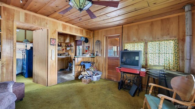 living room featuring carpet flooring, wooden walls, ceiling fan, and wooden ceiling