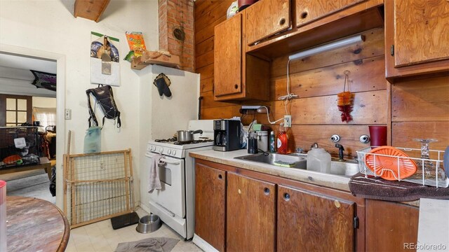 kitchen featuring gas range gas stove, wooden walls, and sink