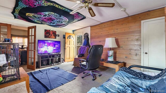 carpeted home office featuring ceiling fan and wooden walls