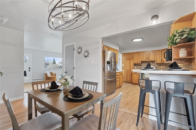 865 S Everett St, Lakewood, CO 80226 - dining area with a baseboard radiator, light wood finished floors, and a notable chandelier