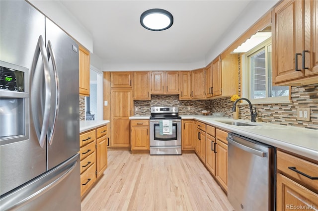 865 S Everett St, Lakewood, CO 80226 - kitchen featuring light countertops, a sink, light wood finished floors, appliances with stainless steel finishes, and backsplash