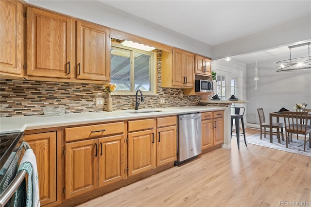 865 S Everett St, Lakewood, CO 80226 - kitchen featuring decorative backsplash, appliances with stainless steel finishes, a sink, light countertops, and light wood-style floors