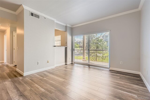 unfurnished room with ornamental molding, wood finished floors, and baseboards